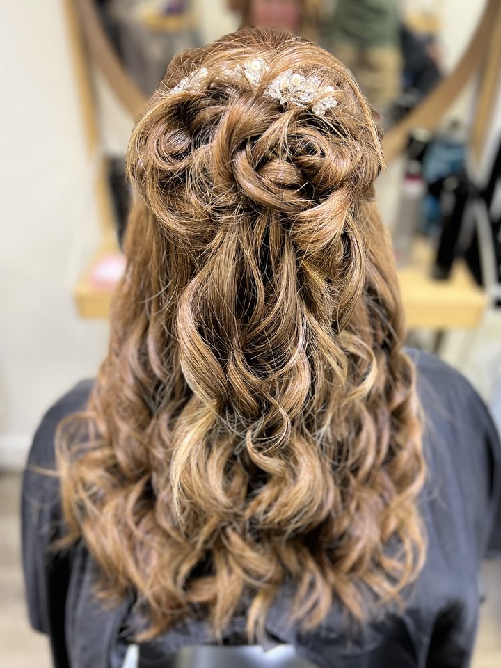 Long brunette waves with a romantic floral braid — bridal-style half-up styling