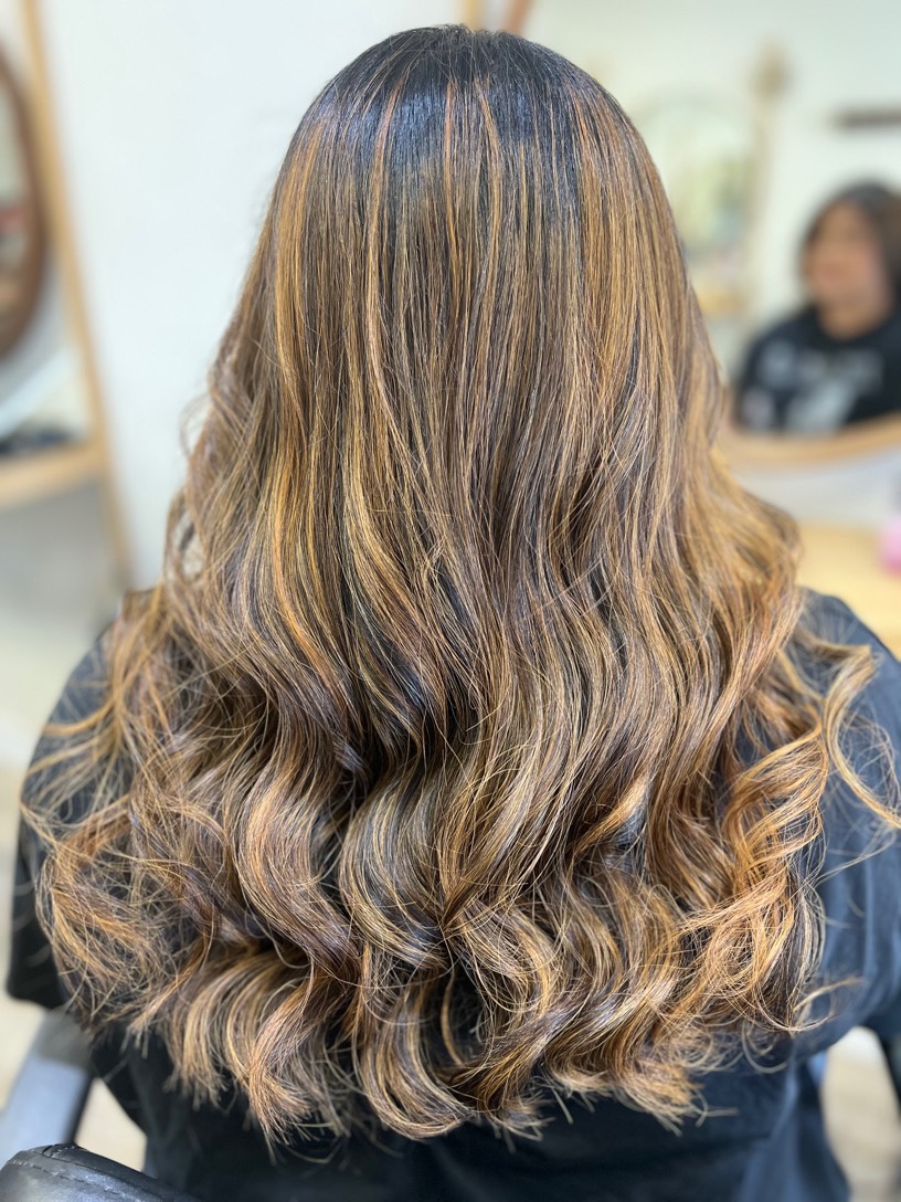 Honey and caramel balayage highlights on long dark brunette hair with soft waves, by Amy at Bloom Salon in Coquitlam